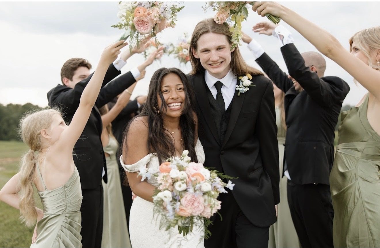 Happy newlywed couple celebrating with friends and bouquets.