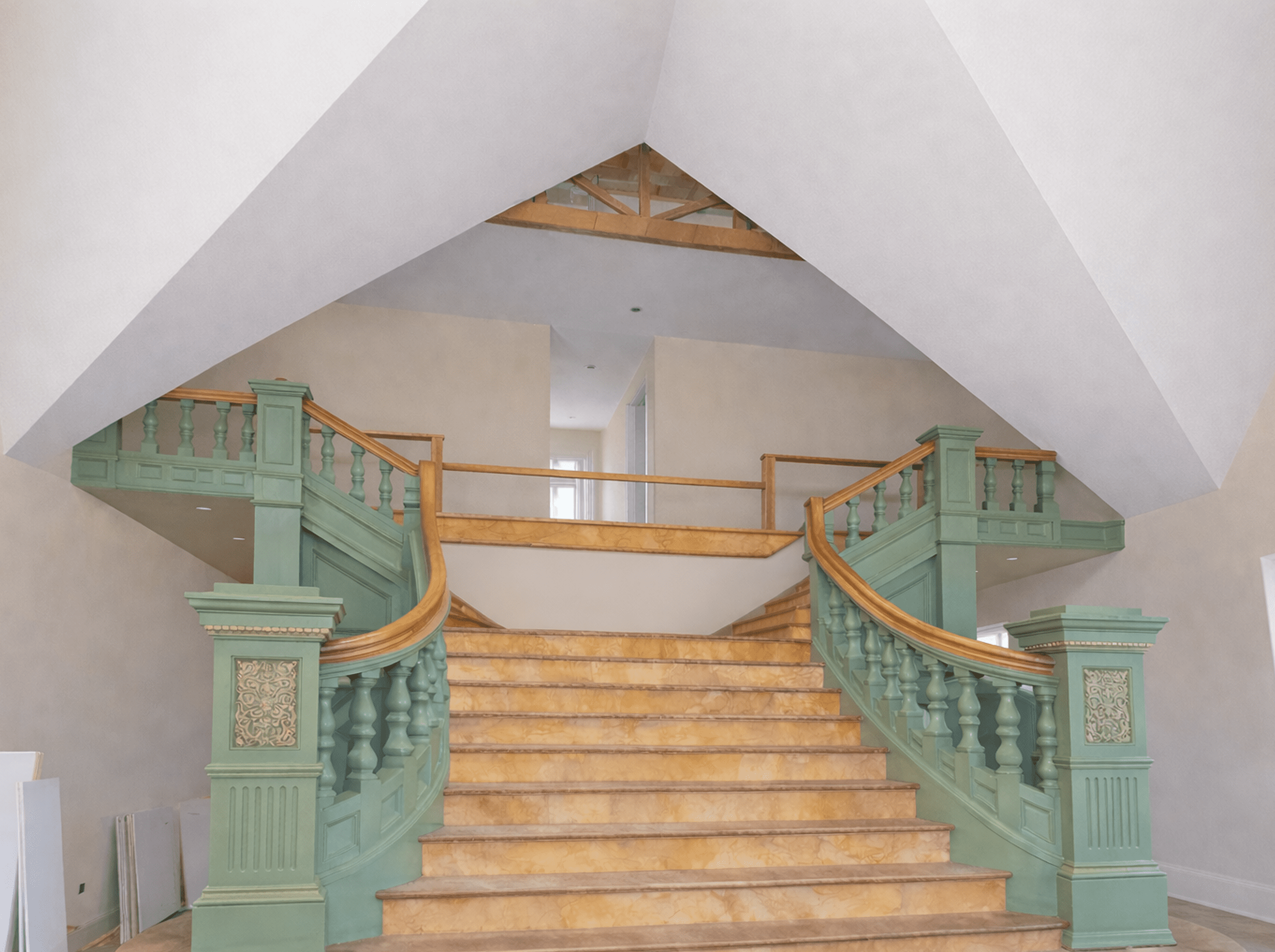Elegant dual staircase with green railings in a spacious interior.