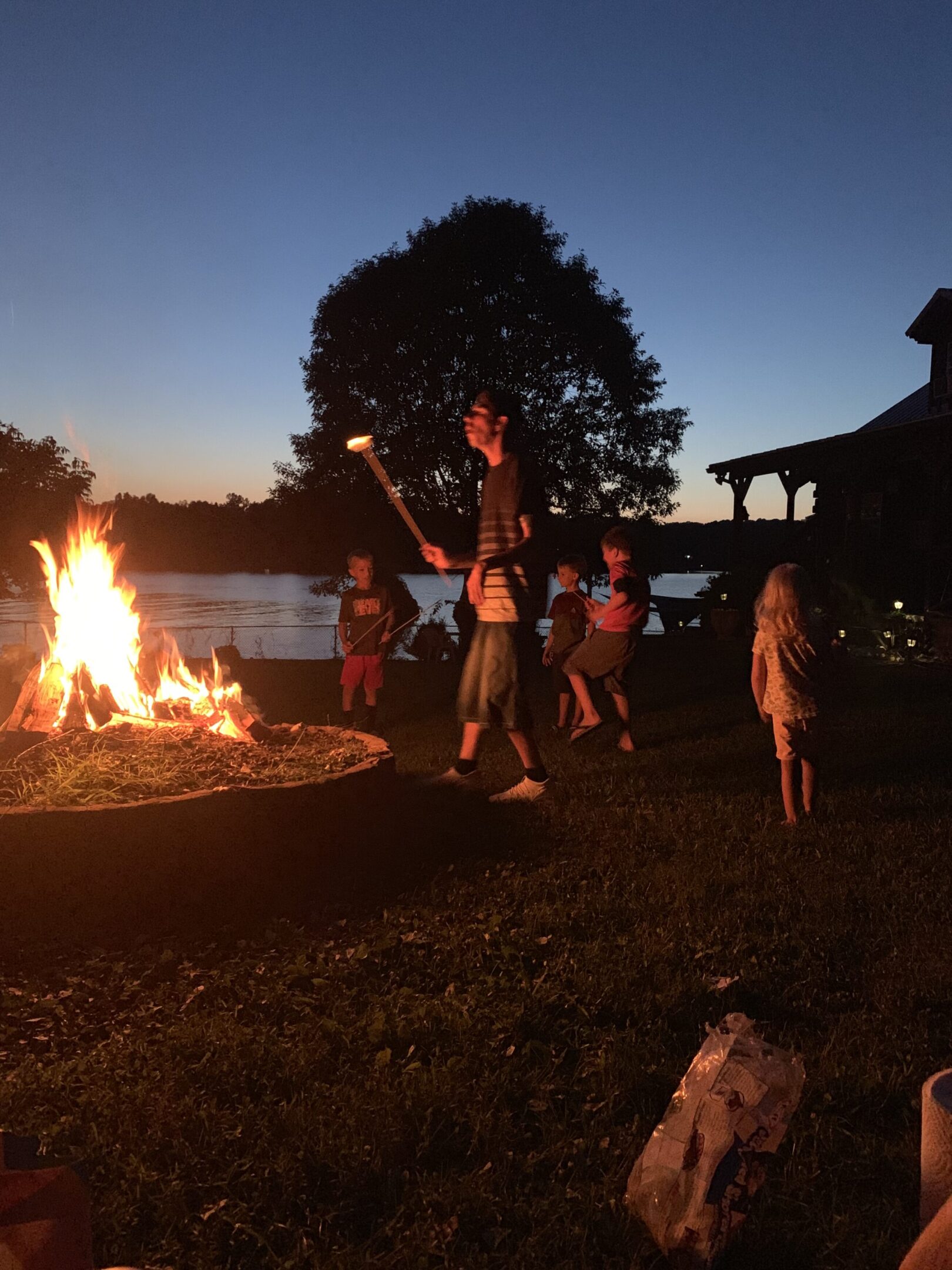 People enjoying a bonfire by a lakeside at dusk.
