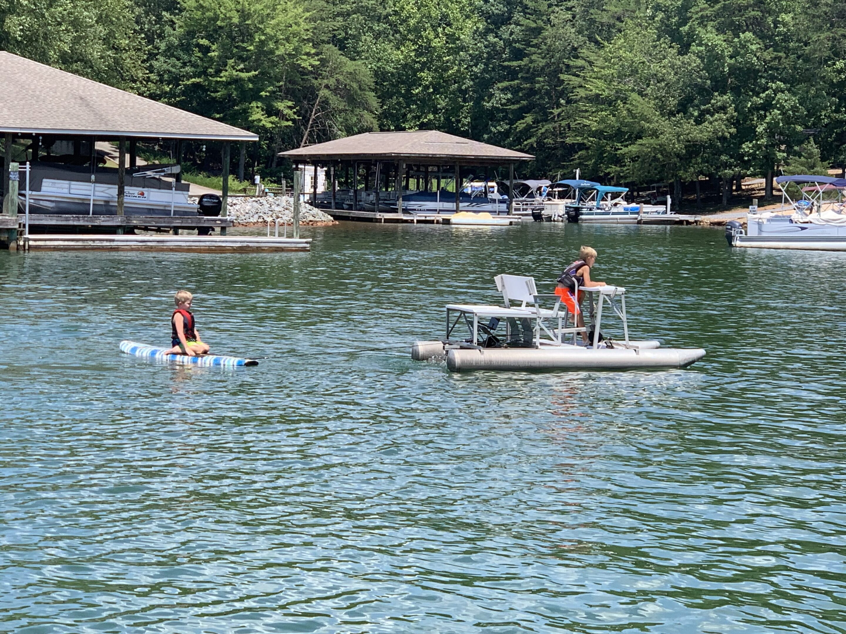 Two people enjoying water activities on a lake with docks in the background.